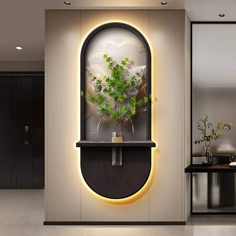 Green Plant Wall Lamp with an illuminated oval black frame, arched relief panel, and central shelf holding a leafy plant