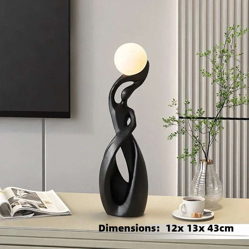 Home Decoration Resin Sculpture floor lamp with a glossy black twisted openwork figure and glowing cream globe bulb.