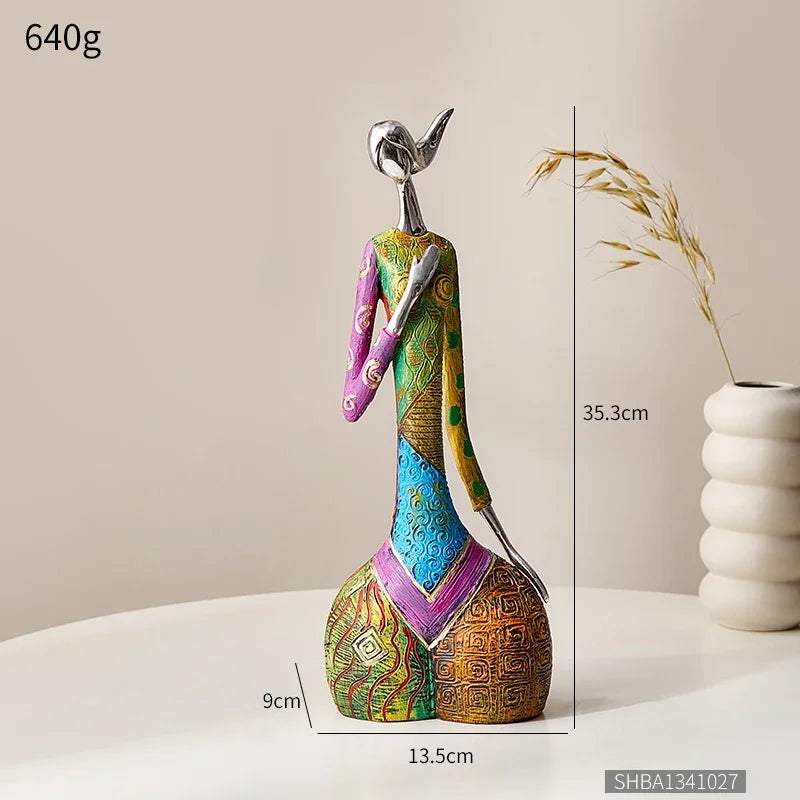 Abstract resin sculpture in vivid multicoloured geometric patterns, featuring a slender figure seated on a round base; Nordic Style Abstract is 35.3 cm tall.