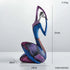 Abstract resin figurine in blue, purple and magenta with geometric patterns, showing a seated figure with raised arms; Nordic Style Abstract is 27 cm tall.