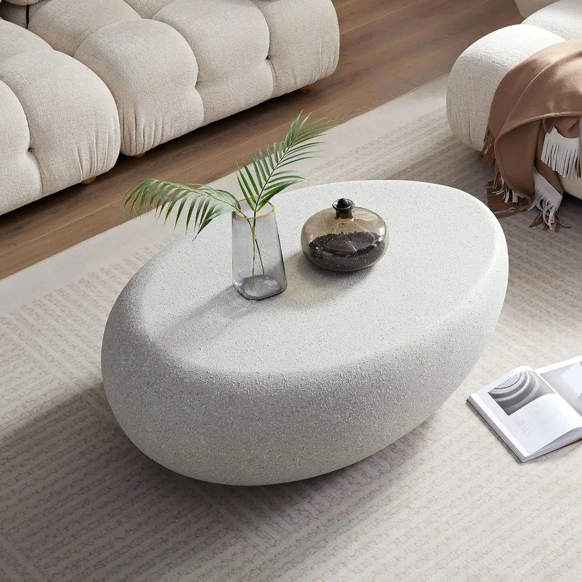 Oval Stone Coffee Table Fiberglass Frame with a light gray, speckled faux-stone surface and sculptural rounded base.
